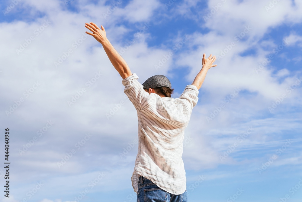 Man with arms raised standing against cloudy sky Man with arms raised standing against cloudy sky