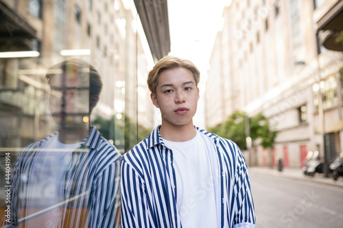 Asian man standing near glass wall in city photo