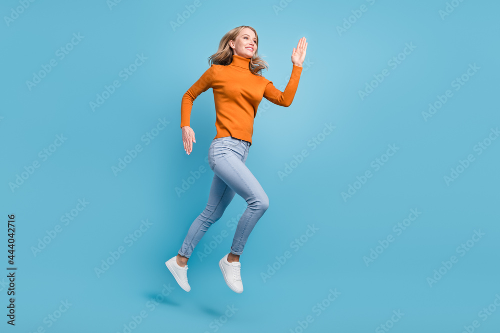 Full body photo of positive pretty nice woman jump up run empty space smile isolated on blue color background