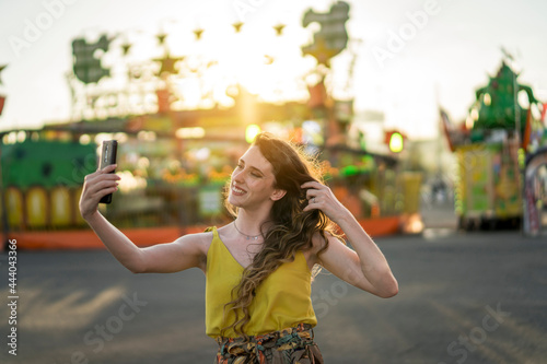 Happy woman taking selfie on smartphone at fairground photo