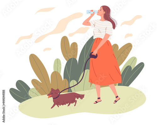 Young woman walking her dog and drinking water