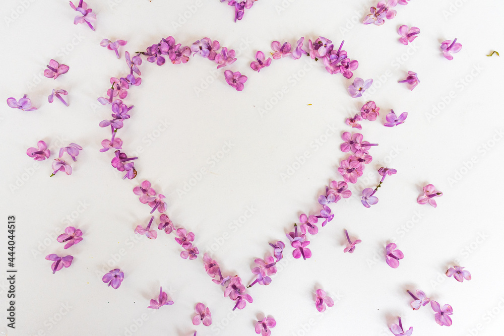 Heart of spring flowers of lilac on a white background. Love symbol for Valentine's Day. Mother's Day. Spring, women's day. Particles of art.
