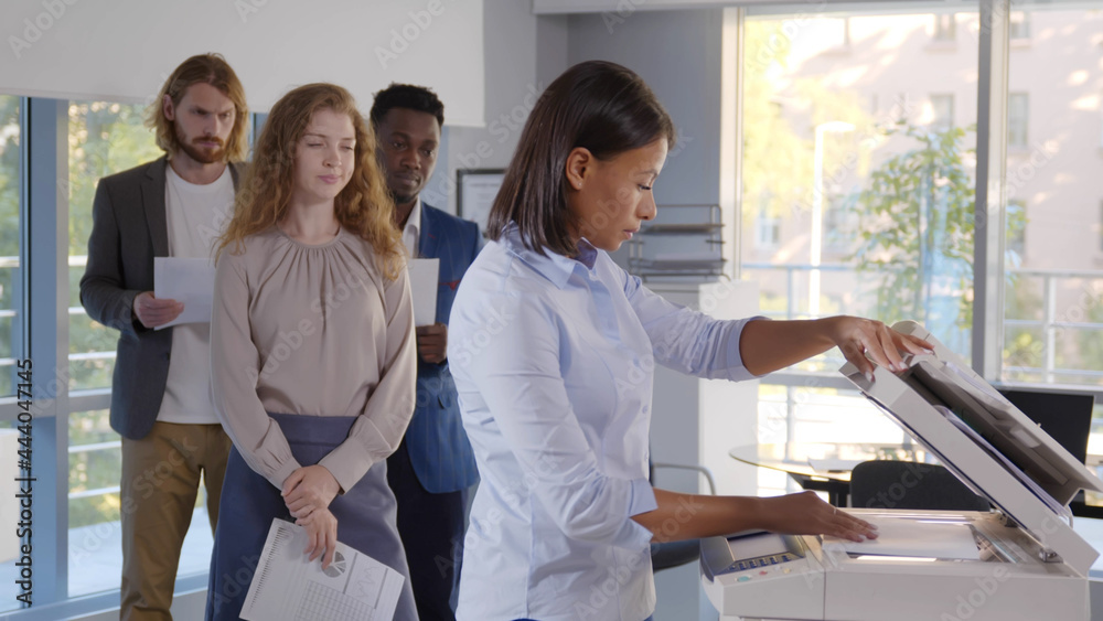 Group of young managers standing in queue for copier at office Group of young managers standing in queue for copier at office