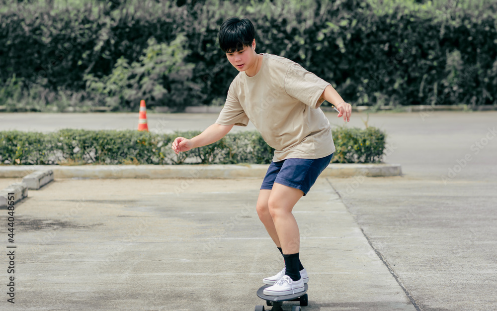 Portrait adult sportive Asian skater wearing hipster shirt with shorts, smiling with happiness, standing on skateboard and playing outdoor with copy space. Activity and Adventure Concept.