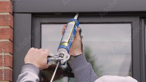Handyman Caulking window with insulation caulk Contract American Worker works on residential home to weatherproof it. Weatherproofing photo