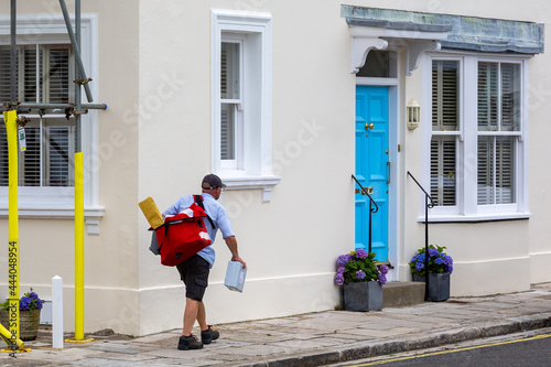A postman or mail man carrying a mail bag delivering post to english homes