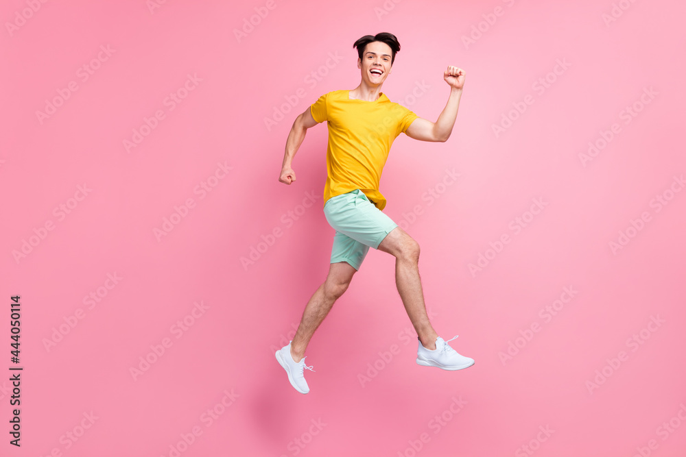 Full size profile side photo of young guy happy positive smile jump up go walk run isolated over pink color background