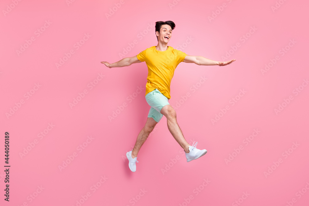 Profile photo of crazy careless active guy jump go look empty space wear yellow t-shirt isolated on pink background