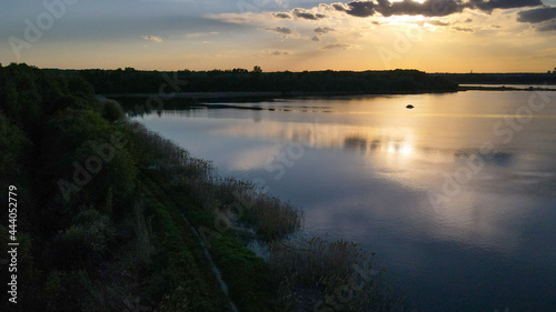 A picturesque sunset over the pond. Panoramic view of the countryside. Design of photo wallpapers, screensavers, covers.