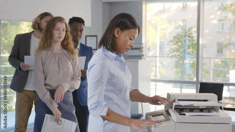 Group of young managers standing in queue for copier at office