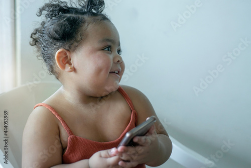 Fotografie Little plump girl, good-humored girl was smiling at someone and holding a smart