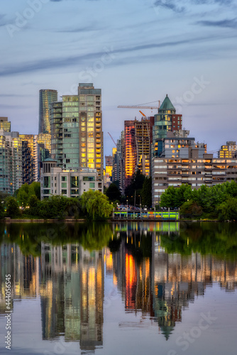 View of Lost Lagoon in famous Stanley Park in a modern city with buildings skyline in background. Colorful Sunset Sky. Downtown Vancouver  British Columbia  Canada.