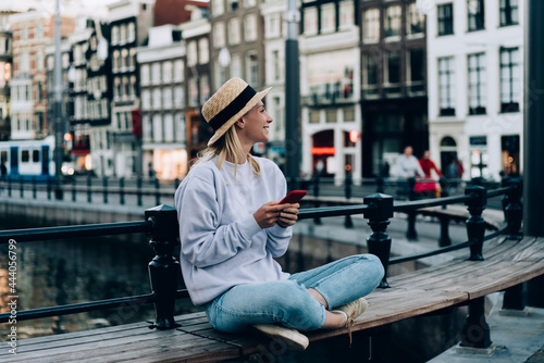 Smiling woman with smartphone sitting on bench