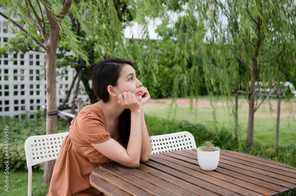 Loneliness young asian woman sitting and looking at something in the garden Loneliness young asian woman sitting and looking at something in the garden