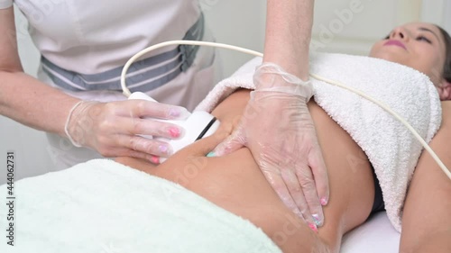 Woman getting ultrasound cavitation treatment by cosmetologist. female client enjoying anti-cellulite procedure at beauty salon. High quality 4k footage photo