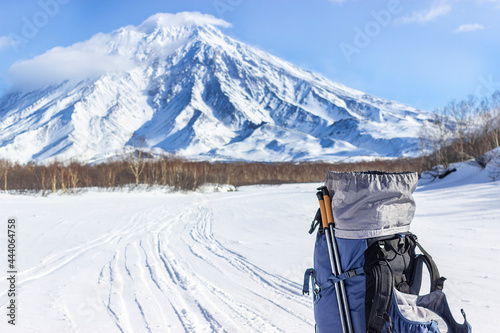 A blue tourist backpack stands on the snow against the background of the Koryaksky volcano at the 