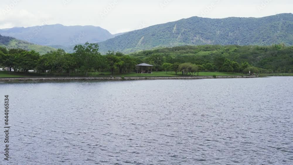 scenic landscape calm waters of a large lake with a stretch of distant green hills at background on a clear day at dapo pond taitung, taiwan. scenic landscape calm waters of a large lake with a stretch of distant green hills at background on a clear day at dapo pond taitung, taiwan.
