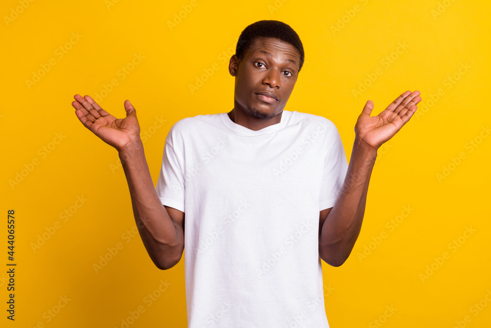 Photo of unsure brunet young guy shrug shoulders wear white t-shirt isolated on yellow color background - obrazy, fototapety, plakaty 
