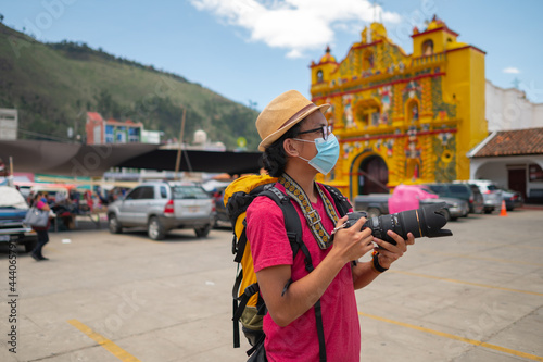 The tourist with his camera in his hands observes the colorful church of San Andrés Xecul Guatemala. photo