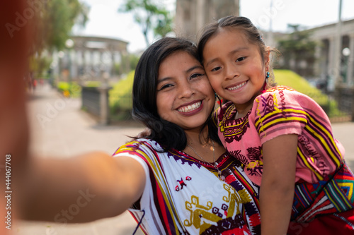 A young mother with her little daughter in a park takes a selfie with the cell phone.