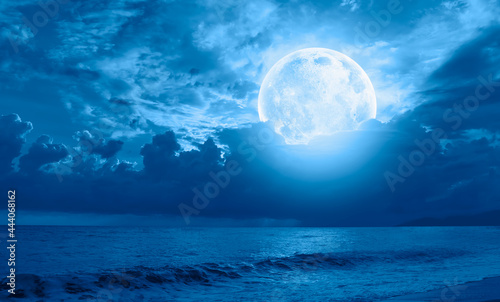 Night sky with moon in the clouds on the foreground calm sea"Elements of this image furnished by NASA