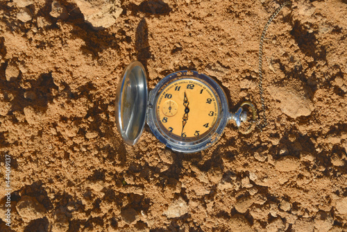 Vintage pocket watch in sandy soil. Earth Day. Global warming is coming.