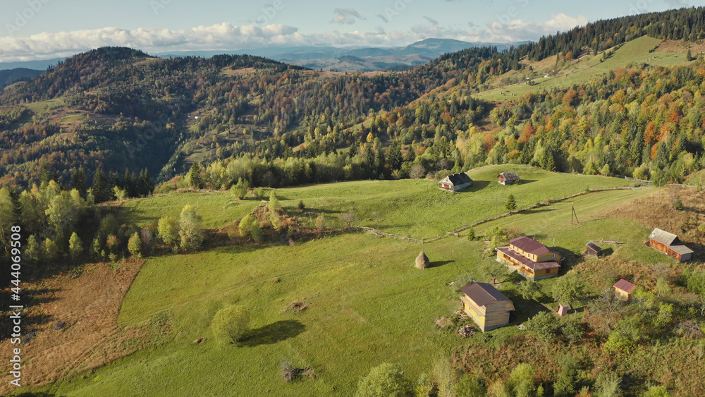 Village at green mountain top aerial. Nobody nature landscape. cottages with rural ways. Cinematic autumn greenery trees, grass. Carpathians mount ranges, Ukraine, Europe. Travel and tourism concept