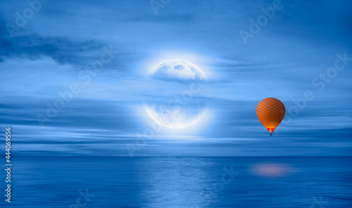 Fototapeta Naklejka Na Ścianę i Meble -  Hot air balloon flying over calm sea moon at night in the background full 
