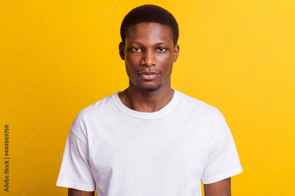 Photo of young serious dark skin man wear white casual t-shirt isolated on shine yellow color background Photo of young serious dark skin man wear white casual t-shirt isolated on shine yellow color background