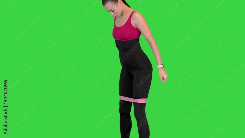 Sporty muscular fitness model doing sit-ups with elastic band on her legs on a Green Screen, Chroma Key. Sporty muscular fitness model doing sit-ups with elastic band on her legs on a Green Screen, Chroma Key.