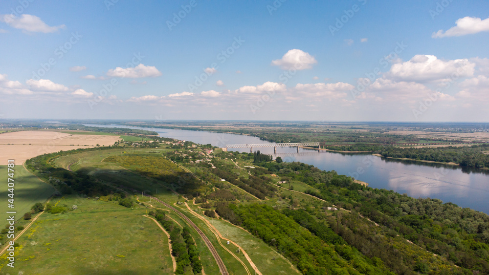 Aerial view of green fields and forest with trees and a river across which the railway bridge. Ukraine Aerial view of green fields and forest with trees and a river across which the railway bridge. Ukraine
