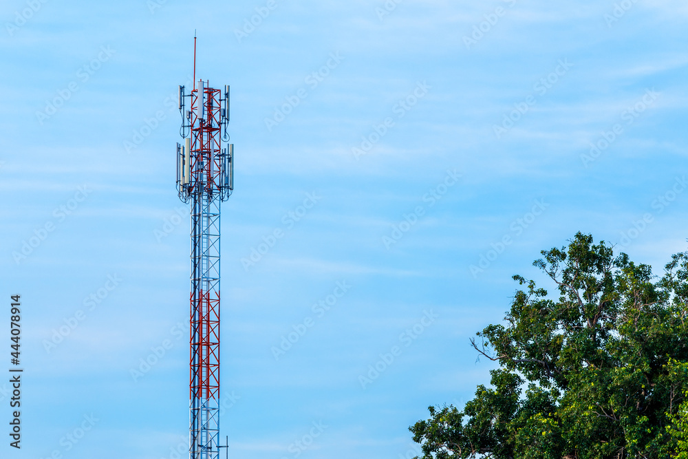 Mobile station receiver antenna tower with fluffy clouds blue sky daylight background.