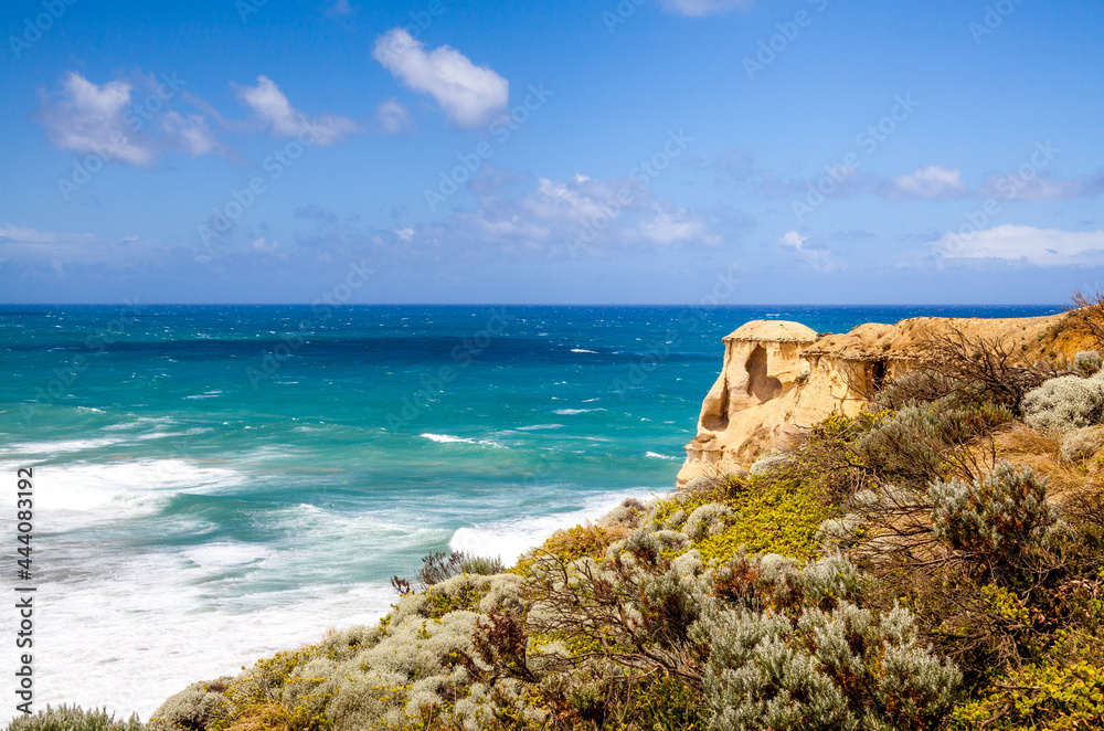The azure sea under the blue sky and the orange rock gazebo on the bushy shore above the ocean. Opposite direction of Twelve Apostles, Australia. Panoramic view from above. 