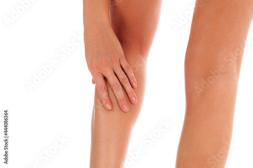 Woman touches her painful shin, isolated on white background