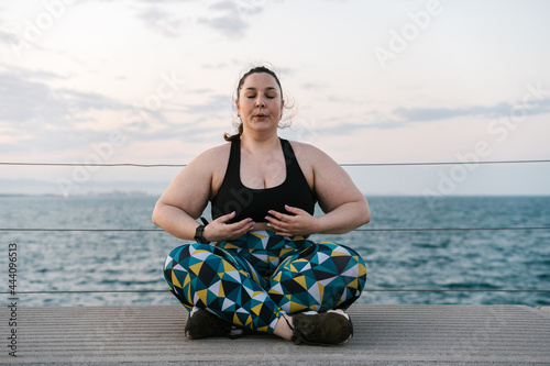 Curvy woman doing breathing exercise on embankment photo