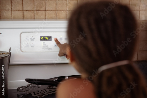 Girl setting the temperature on an oven. photo