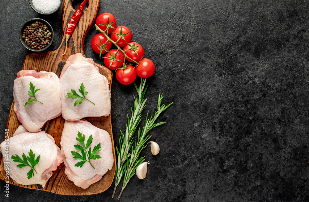 raw chicken thighs with spices and herbs on a stone background with a copy of the space for your text