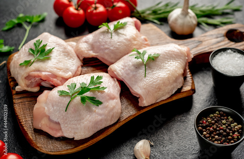 raw chicken thighs with spices and herbs on a stone background