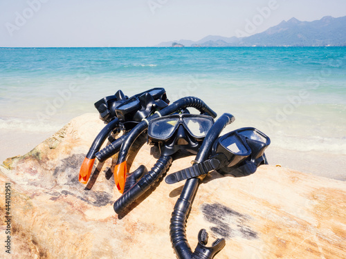 snorkels mask are on timber with the sand beach and sea background