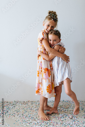 Two sisters giving a hug while playing with confetti photo