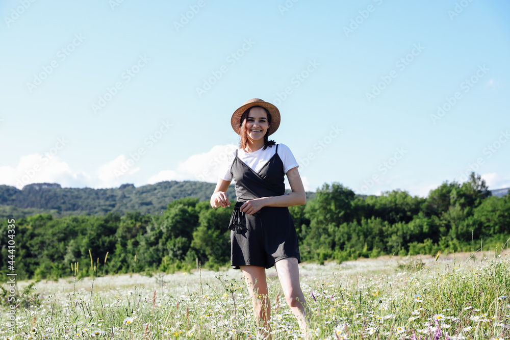 Beautiful woman in dress walks travels on the field of daisies