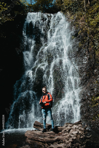 male traveler stands at a waterfall in the forest
