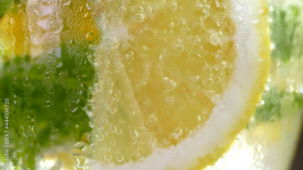 Refreshing soft drink with ice. Mojito with lemon and mint in a glass. Carbonated water close up. Drops of cold dew on a glass.