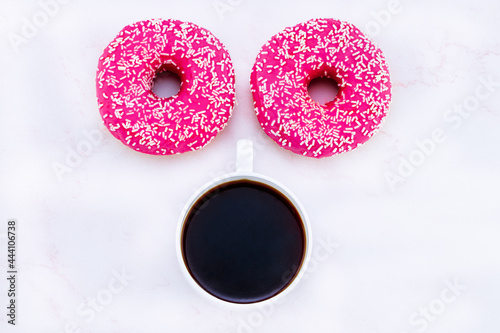 donuts like eyes and a cup of coffee. Top view. Minimalist concept morning