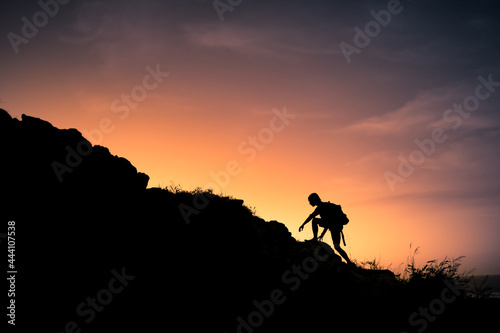 Hiker silhouette starting his climb up the mountain. Outdoor adventure, motivation and active sport concept. 