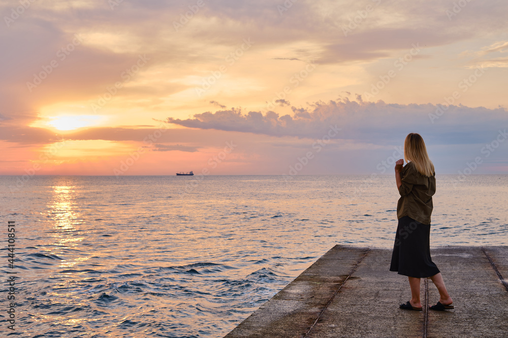 Wunschmotiv: Beautiful girl stands by the sea and looks at the dawn. Girl in travel. Amazing scenic