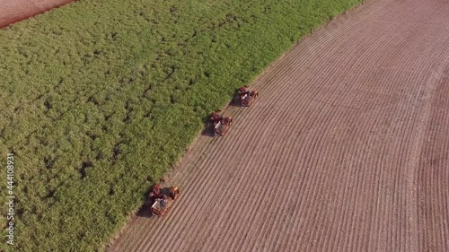 Sugar cane hasvest plantation with three machines view aerial photo