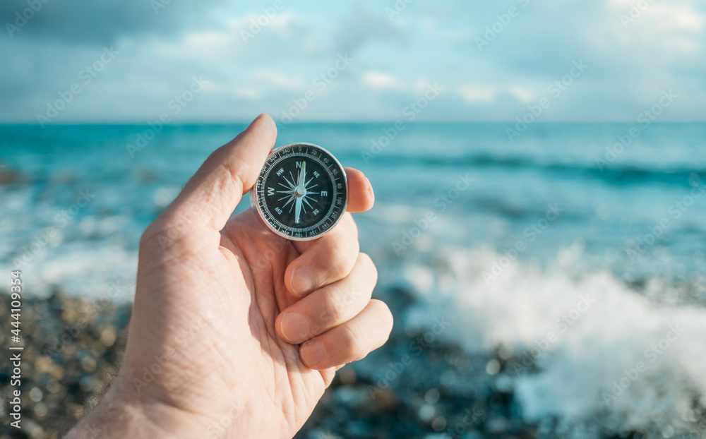 Travel and freedom concept. Compass in hand in the background the waves and the sea. Travel and freedom concept. Compass in hand in the background the waves and the sea.