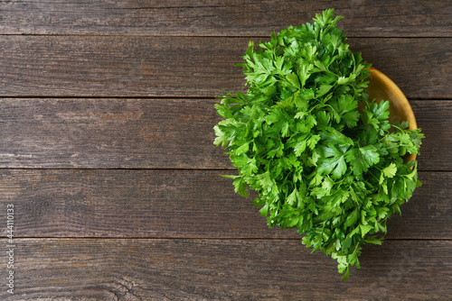 fresh parsley in a wooden bowl on the table, top view.