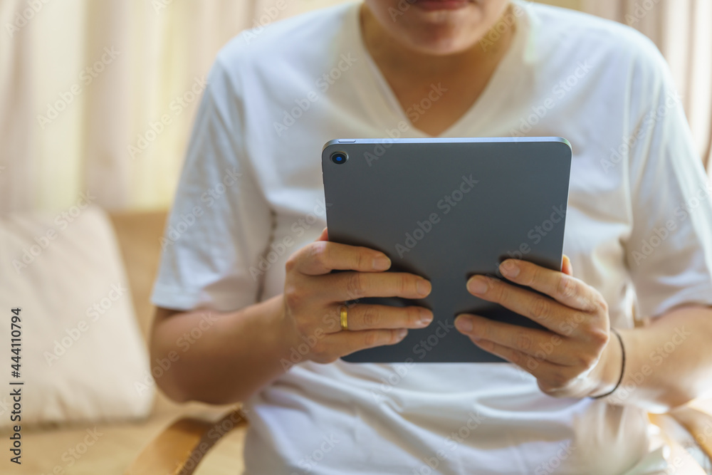 Technology Concept. Closeup of computer tablet in Asian man hand in living room